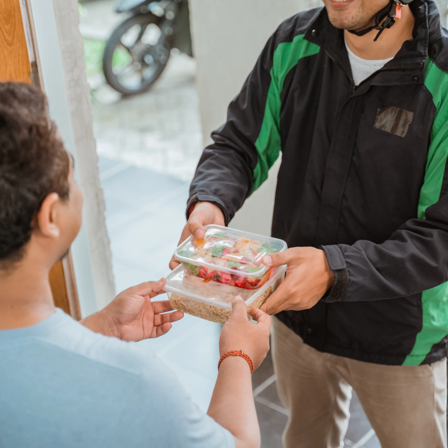 Two men casually chat as one hands a box to the other.